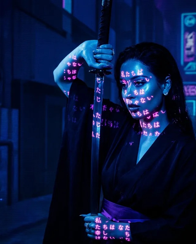 A striking editorial photograph featuring a figure in dark attire holding a sword, illuminated by blue and purple projections of Japanese text on their skin. The moody atmosphere evokes a sense of mystery and intensity, enhanced by the urban backdrop.