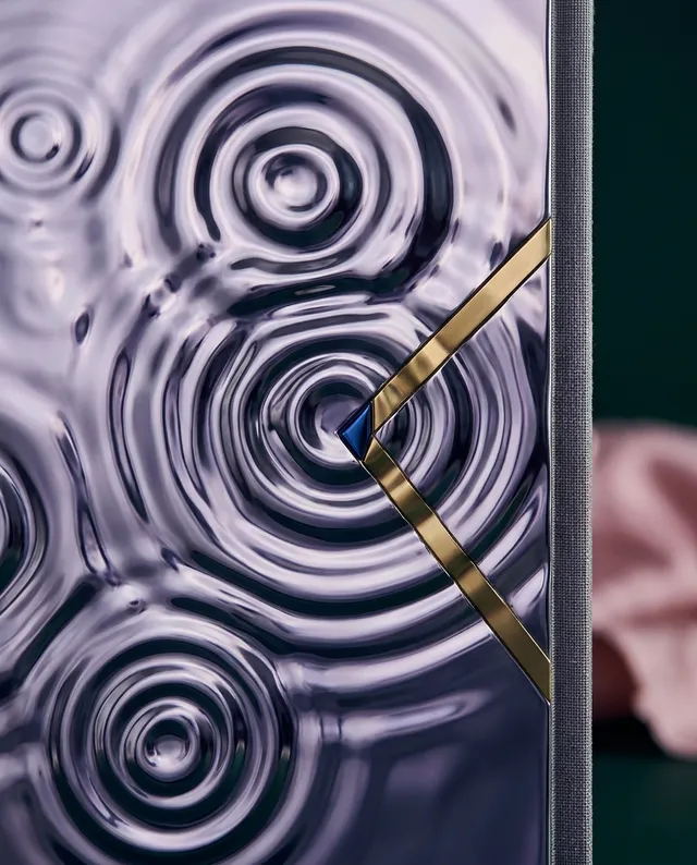 A close-up shot of a sleek, modern object featuring swirling, reflective surfaces and elegant gold accents, exuding a contemporary and luxurious mood. The dominant colours are deep purples and gold, creating a sophisticated visual impact.