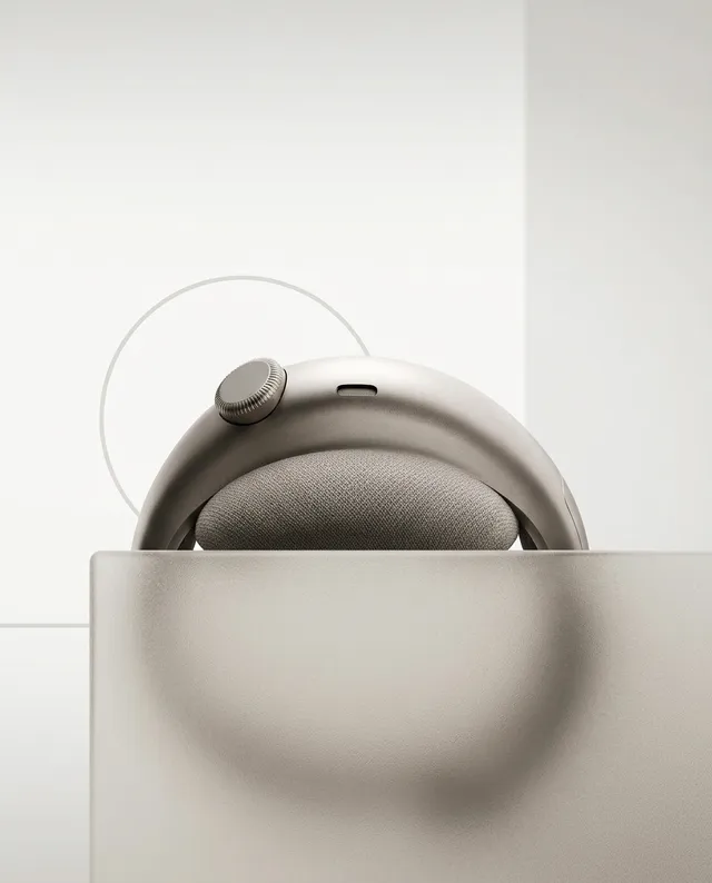 A minimalist product shot of a sleek pair of headphones, featuring soft curves and neutral shades of silver and beige against a clean, light background. The design evokes a calm and modern aesthetic.