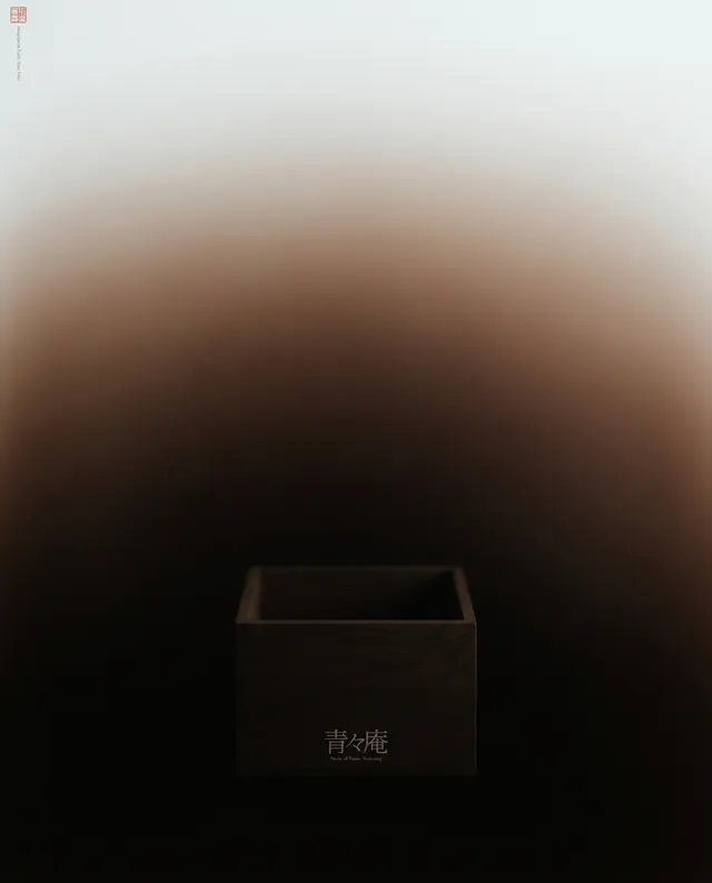 A minimalist editorial photograph features a dark wooden box with subtle engraved text, set against a gradient background that transitions from deep brown to soft cream. The composition evokes a serene and contemplative mood, emphasizing simplicity and elegance.