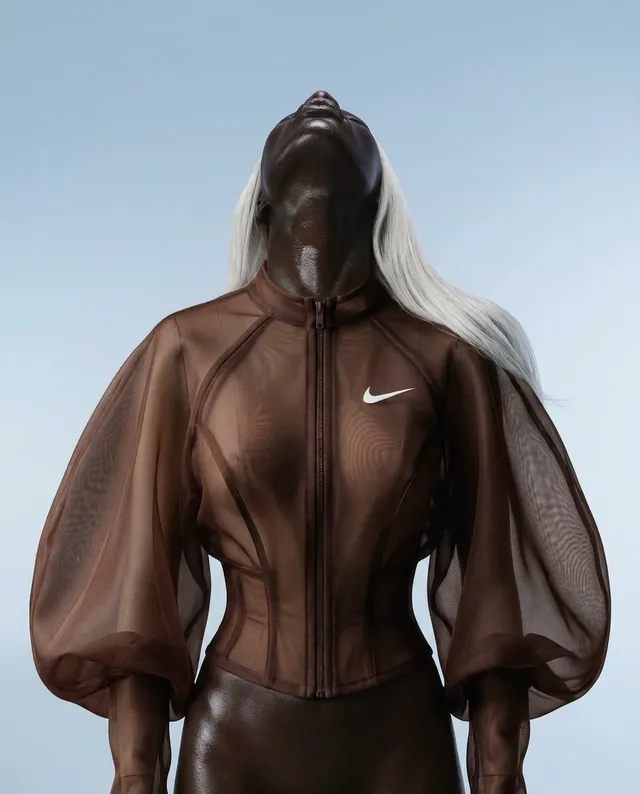 This image features a woman in a sheer, form-fitting brown outfit with large puffed sleeves, showcasing a modern, fashion-forward aesthetic. The mood is luxurious, with a clean backdrop that complements the dominant brown tones.