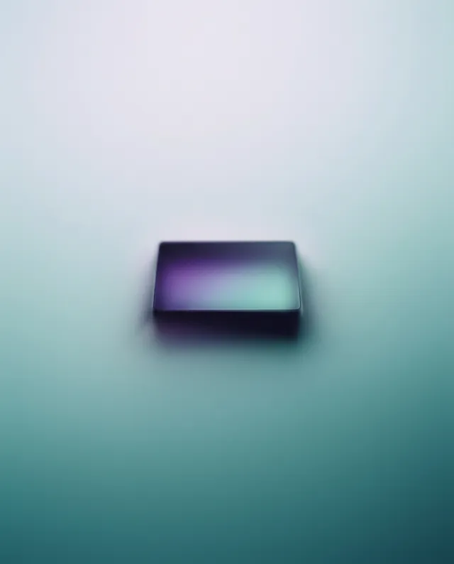 A minimalist digital artwork featuring a sleek, dark phone or tablet resting on a gradient background that transitions from soft purple to light blue, evoking a calm and futuristic mood. The smooth, ethereal quality enhances the device's modern aesthetic.