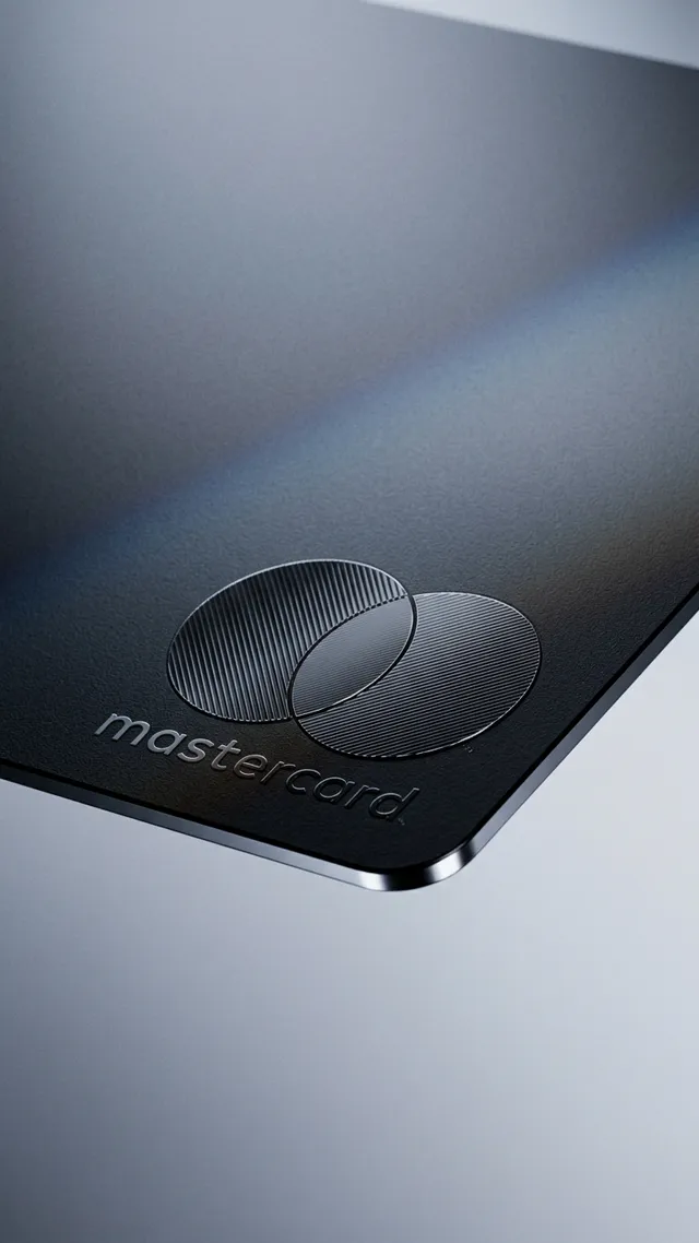 A sleek, close-up shot of a Mastercard credit card featuring a minimalist design and a smooth matte finish. The image exudes a modern, professional mood with cool tones of black and grey, accentuated by subtle reflections.