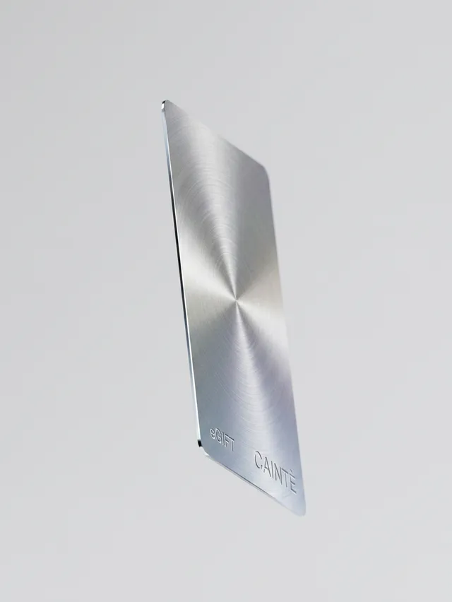 A sleek, metallic card with a brushed finish floats against a minimalistic white backdrop, embodying a modern and sophisticated aesthetic. The design highlights a sense of elegance and innovation, with a focus on smooth lines and a subtle shine.