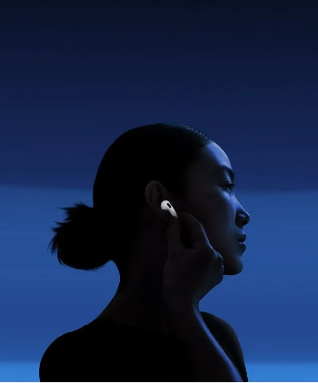 A silhouette of a woman with a bun gently touching her ear, showcasing wireless earbuds against a deep blue gradient background. The image conveys a modern, minimalist aesthetic, emphasizing technology and tranquility.
